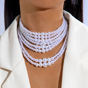Detailed view of luxury multilayered faux pearl necklace on a white blazer model
