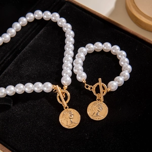 Dettaglio del set collana e bracciale di perle con chiusura OT e ciondolo a moneta