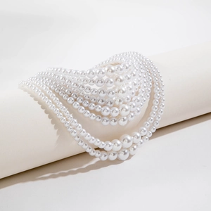 Detail shot of multi-layer white faux pearl necklace draped on a white cylindrical stand