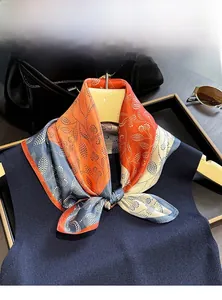 Detail of 100% mulberry silk scarf featuring blue and orange paisley print on a navy vest