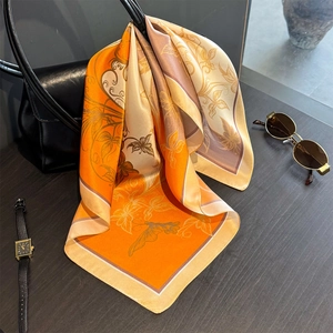 Elegant 100% mulberry silk square scarf with floral pattern draped on a black handbag