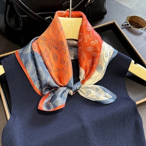 Paisley floral print silk scarf styled on navy vest with luxury city accessories