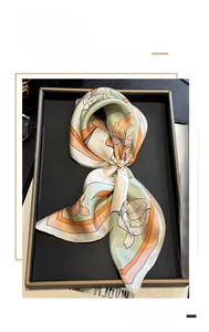 Detail of elegant floral silk scarf in green and orange with pearl buckle accessory