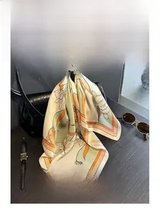 Silk scarf with floral patterns draped on a black leather handbag with accessories
