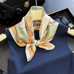 Elegant floral silk scarf tied over blue knitwear for a vintage business casual look