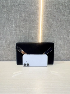 Front detail of black velvet clutch showing silver V-shaped trim and phone storage capacity