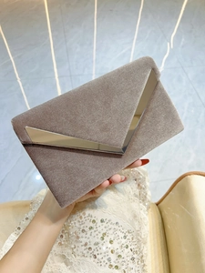 Detailed view of champagne velvet evening clutch with elegant V-shaped metal trim
