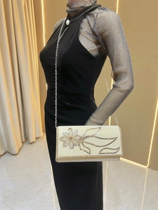 Macro detail of elegant pearl beaded evening clutch with crystal floral metal frame