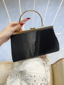 Detail of pleated black evening clutch bag with round gold metal handle for parties
