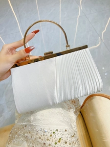 Detail of white pleated evening clutch featuring golden metal handle and satin texture