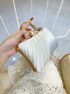 White satin evening clutch bag with rhinestone handle and pearl clasp held by a model