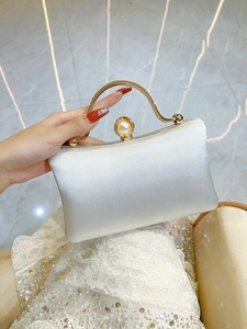 Detail of elegant off-white satin clutch with gold handle and large pearl clasp