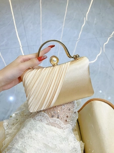 Close-up of champagne silk clutch with pearl clasp and sparkling rhinestone details