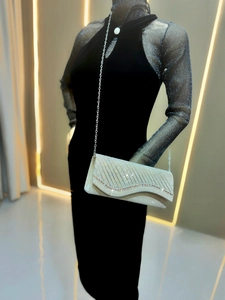 Close-up of silver glitter clutch with wavy pleats and rhinestones for formal evening wear