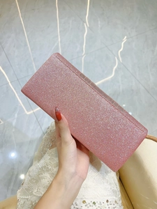 Handheld view of a pink glitter evening clutch bag paired with a white lace dress