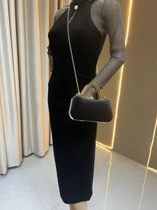 Elegante pochette in velluto nero con manico dorato e catena su manichino con vestito