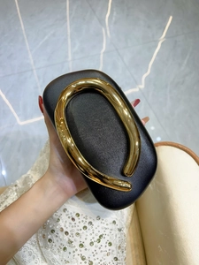 Detail of black Saffiano evening bag featuring a minimalist round gold metal handle