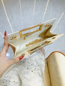 Beige woven clutch bag with gold handle and chain strap seen from an overhead view
