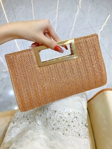 Detail of woven straw clutch bag with modern rectangular gold metal handle and texture