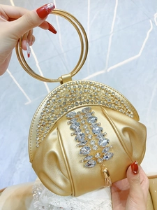Détail d'une pochette dorée ornée de strass brillants et de pampilles métalliques fines