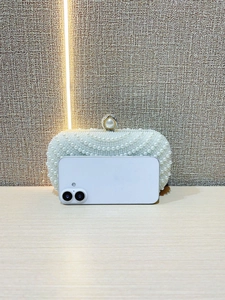 Detail of beaded pearl evening clutch next to smartphone for size comparison