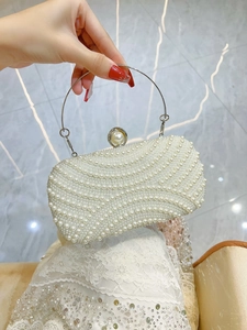 Close-up of white pearl evening bag with silver round handle and wave pattern texture