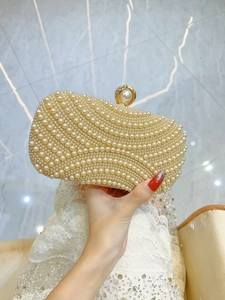 Close-up of elegant pearl evening clutch with wavy texture and gold metal clasp