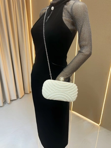 Detailed close-up of a white pearl clutch with wave pattern and large pearl clasp lock