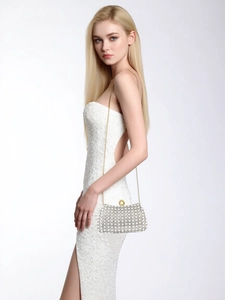 Chic rhinestone evening clutch bag with gold chain strap worn over a white sequin dress