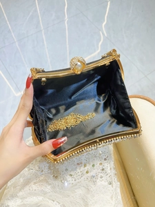 Elegant black evening clutch with gold metal frame, pearl clasp, and metal chain strap