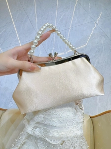 Détail de la pochette de soirée en satin champagne avec anse en perles et fermoir en métal