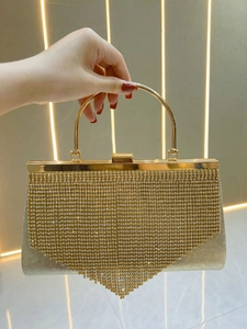 Close-up of golden evening bag featuring sparkling rhinestones and fringe tassels details