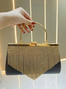 Detail of evening clutch featuring long gold rhinestone tassels and a metal ring handle
