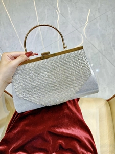 Close-up of sparkling rhinestone tassels and gold circular handle on silver evening bag