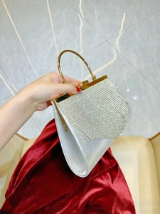 Close-up of sparkling silver rhinestone evening clutch bag with golden ring handle