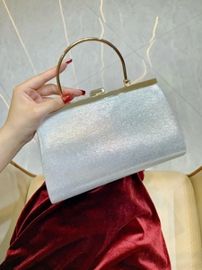 Detail view of a silver glitter evening bag with a circular gold metal handle and frame