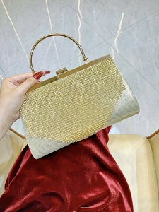 Close-up of champagne gold clutch featuring rhinestones and a round metal handle
