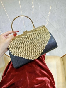 Close-up of black evening bag with gold rhinestones held in hand against red velvet
