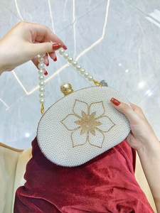 Detailed view of pearl evening bag featuring gold sequin flower and elegant handle