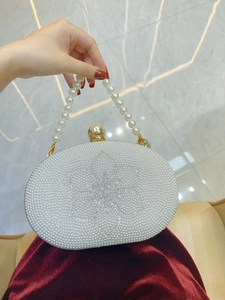 Detail of white pearl evening clutch with center flower design and elegant beaded handle