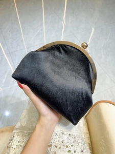 Close-up of black velvet evening clutch with golden metal frame and sphere clasp