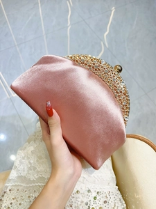 Detailed close-up of pink satin evening clutch with sparkling rhinestone metal frame