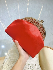 Detail of red satin clutch with gold hollow frame and sparkling white rhinestones