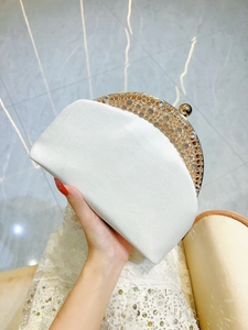 Detail of white satin evening clutch with gold filigree and sparkling rhinestones