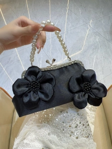 Détail du sac de soirée en satin noir avec fleurs en tissu, anse en perles et cadre strass