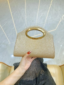 Detail of a luxury gold glitter evening clutch bag with an oval metal handle for women