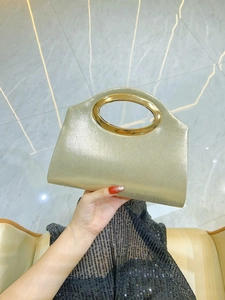 Detail of champagne gold glitter clutch with metallic oval handle for evening wear