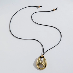 Detalle del colgante de gota dorada con agujeros huecos en un cordón encerado negro