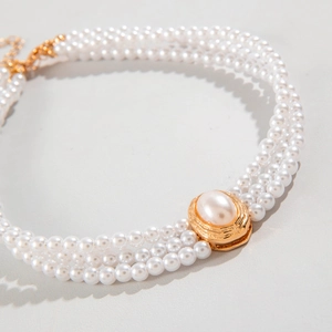 Detail of elegant three-layer pearl necklace with a vintage gold oval pendant clasp