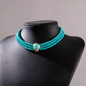 Detail of triple-layer turquoise beaded choker necklace with vintage gold oval pendant